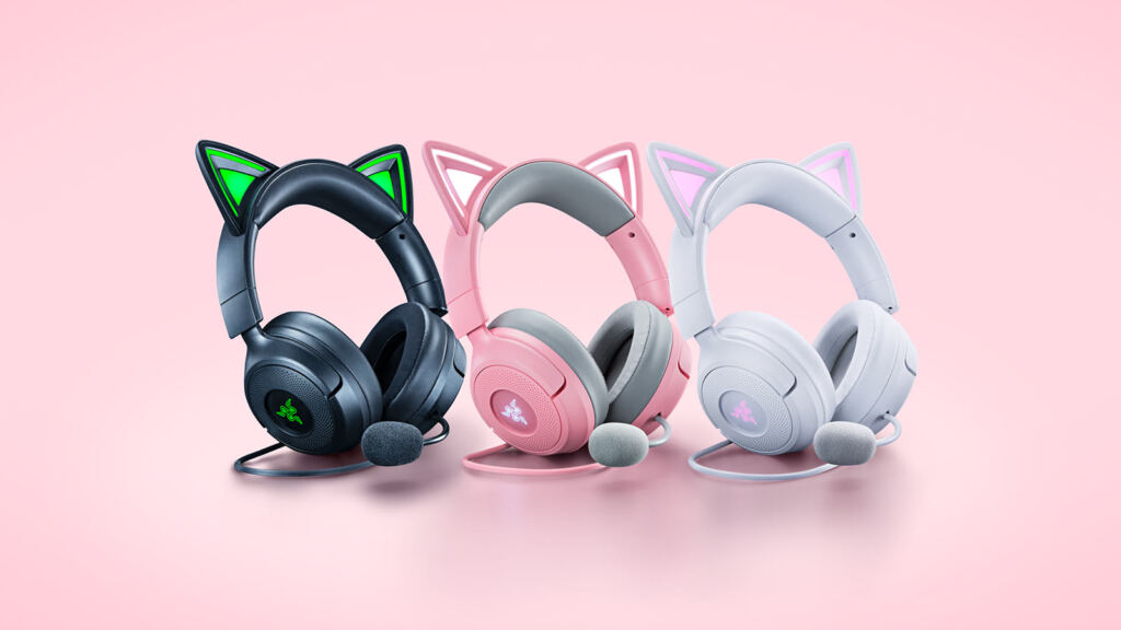 Três headsets Razer Kraken Kitty V3 nas cores preta, rosa e branca, com orelhas de gato iluminadas